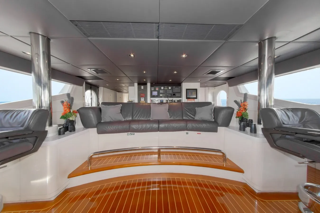 Oceanfast 164 High Occupancy yacht bridge with grey sofa positioned behind helm seats