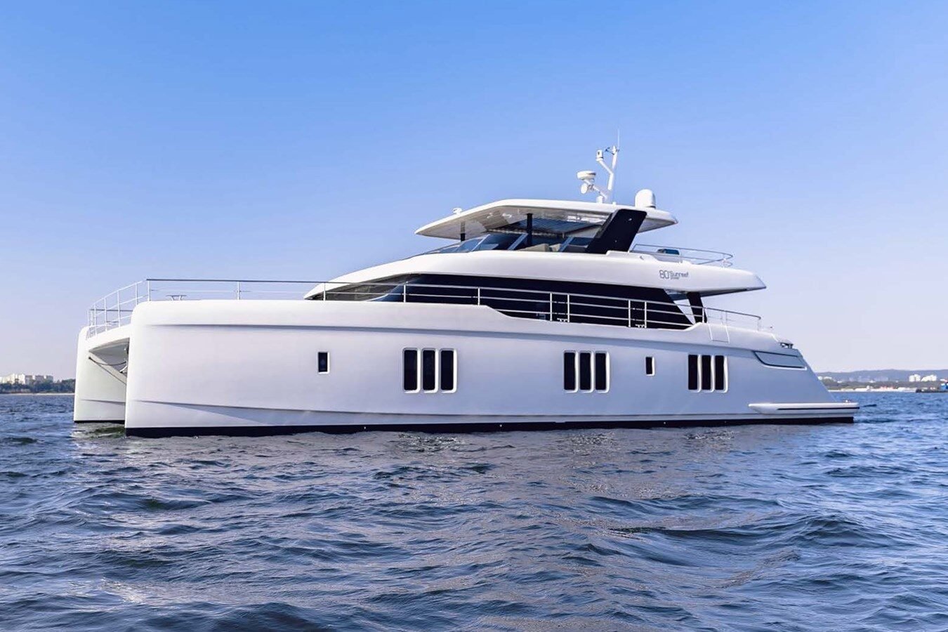 Side profile view of Sunreef Yachts 80 Kokomo peacefully anchored in calm blue waters.