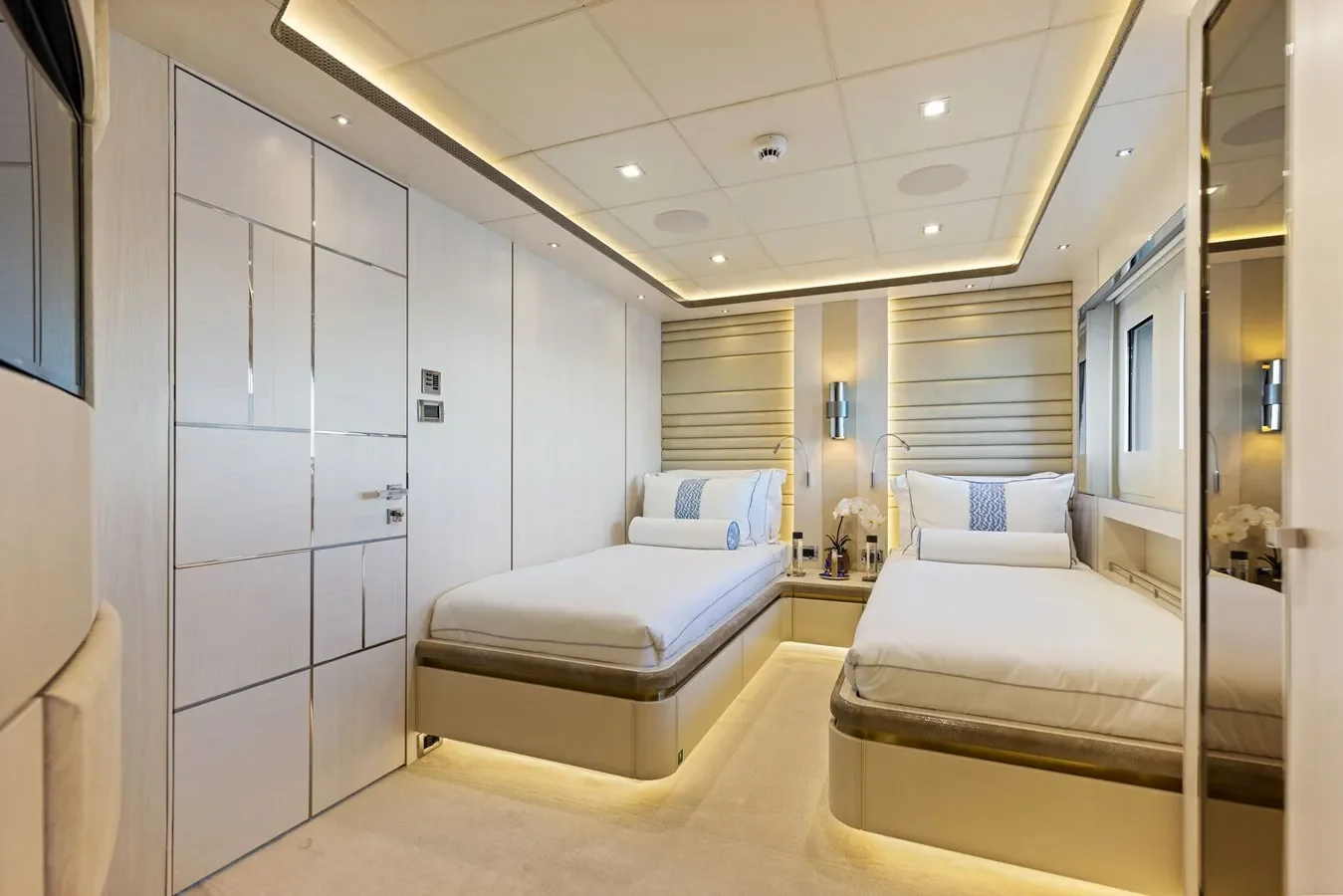 Yacht guest bedroom with two single beds, refined décor, and ambient lighting.