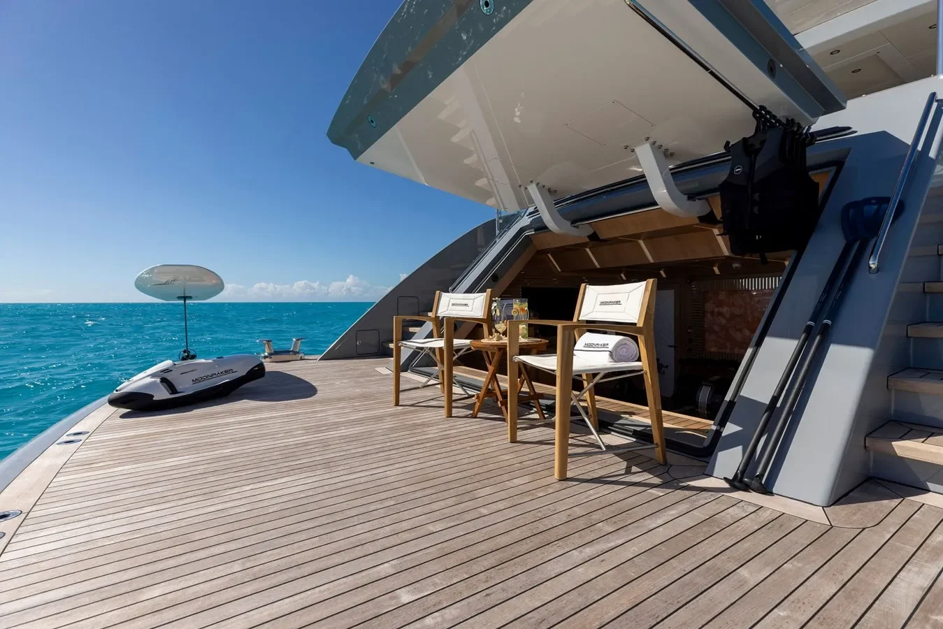 Spacious yacht beach club with lounge chairs and water toys by the sea.