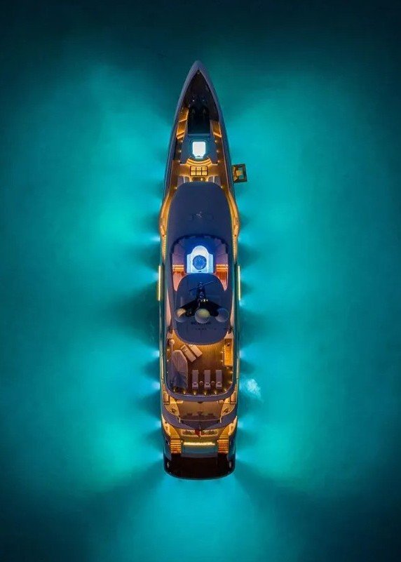 Top aerial night view of Bilgin Yachts 156 “Moonraker” illuminated with glowing deck lights against the dark sea.