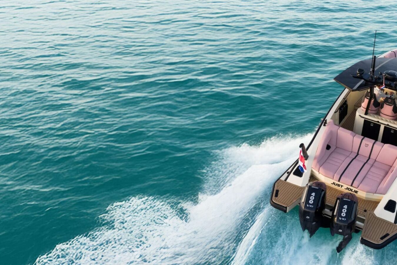 Aerial rear view of the LEKKER 38 yacht cruising at speed with open deck seating and twin outboard engines