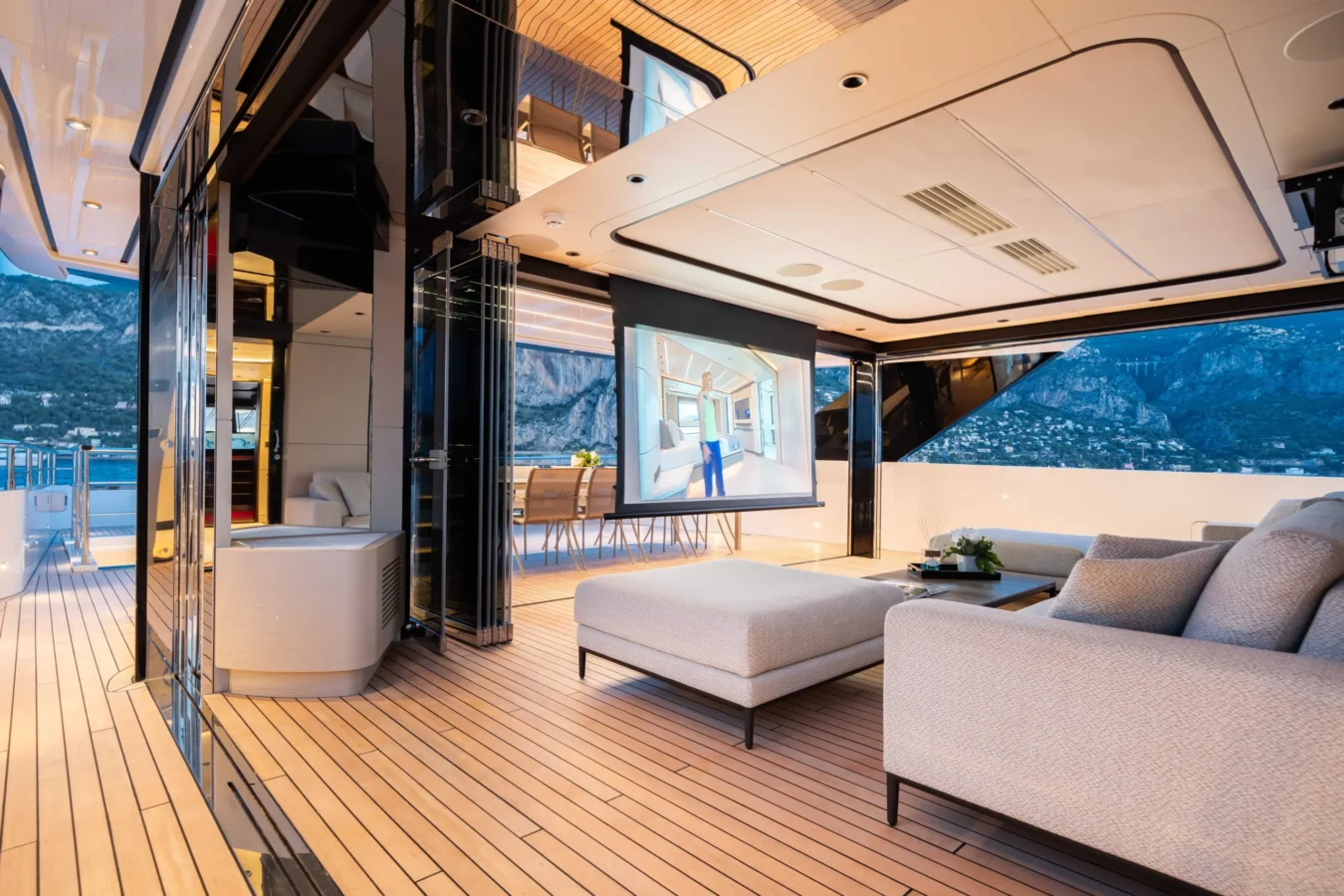 Ocean King Ducale 120 aft salon with open glass doors, indoor-outdoor lounge seating, and evening ocean views