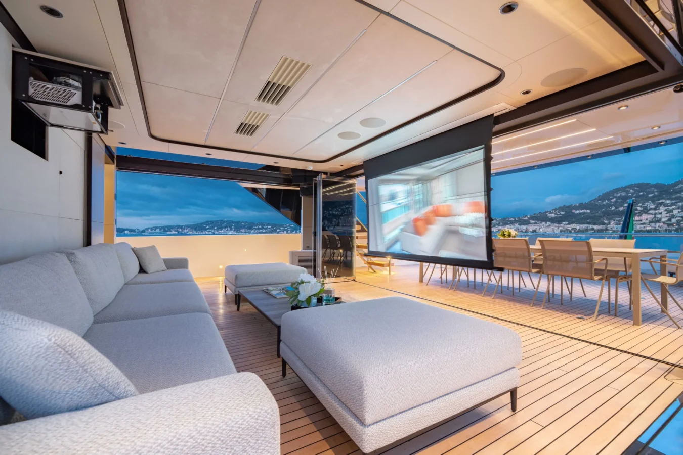 Ocean King Ducale 120 covered aft deck lounge with outdoor seating, dining area, and drop-down cinema screen