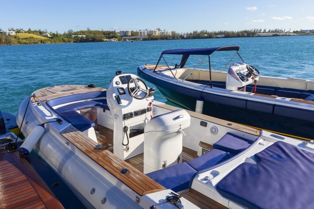 Two modern motorboats with blue seats docked, near an Abeking & Rasmussen HBC Yacht for Charter on clear blue water.