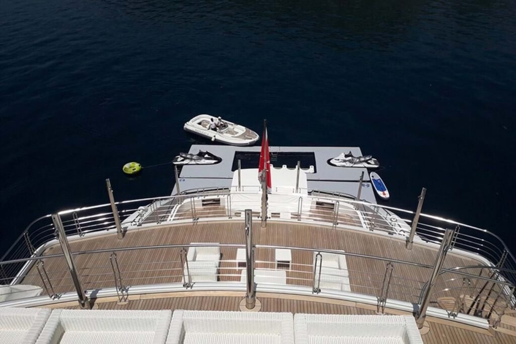 View from the Neorion Moonlight II Yacht for Charter showing water toys, jet skis, a tender, and flag over deep blue water.