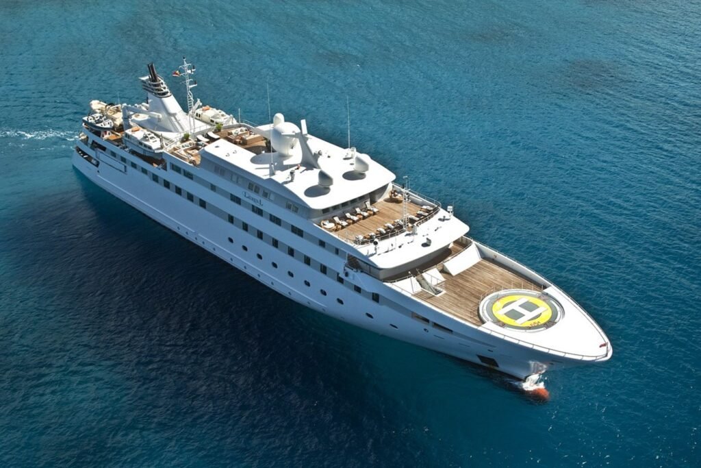 The Cassens-Werft PV Lauren L Yacht, a large white luxury vessel with a helipad, cruises on clear blue water.