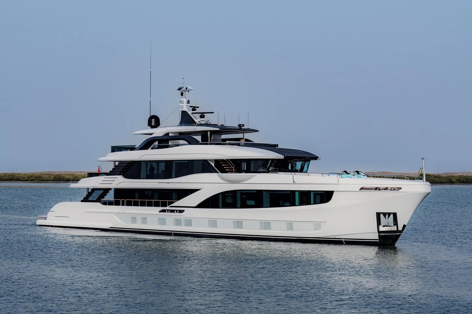 A Majesty 145 superyacht cruises on calm water, featuring a modern white multi-deck design with tinted windows.