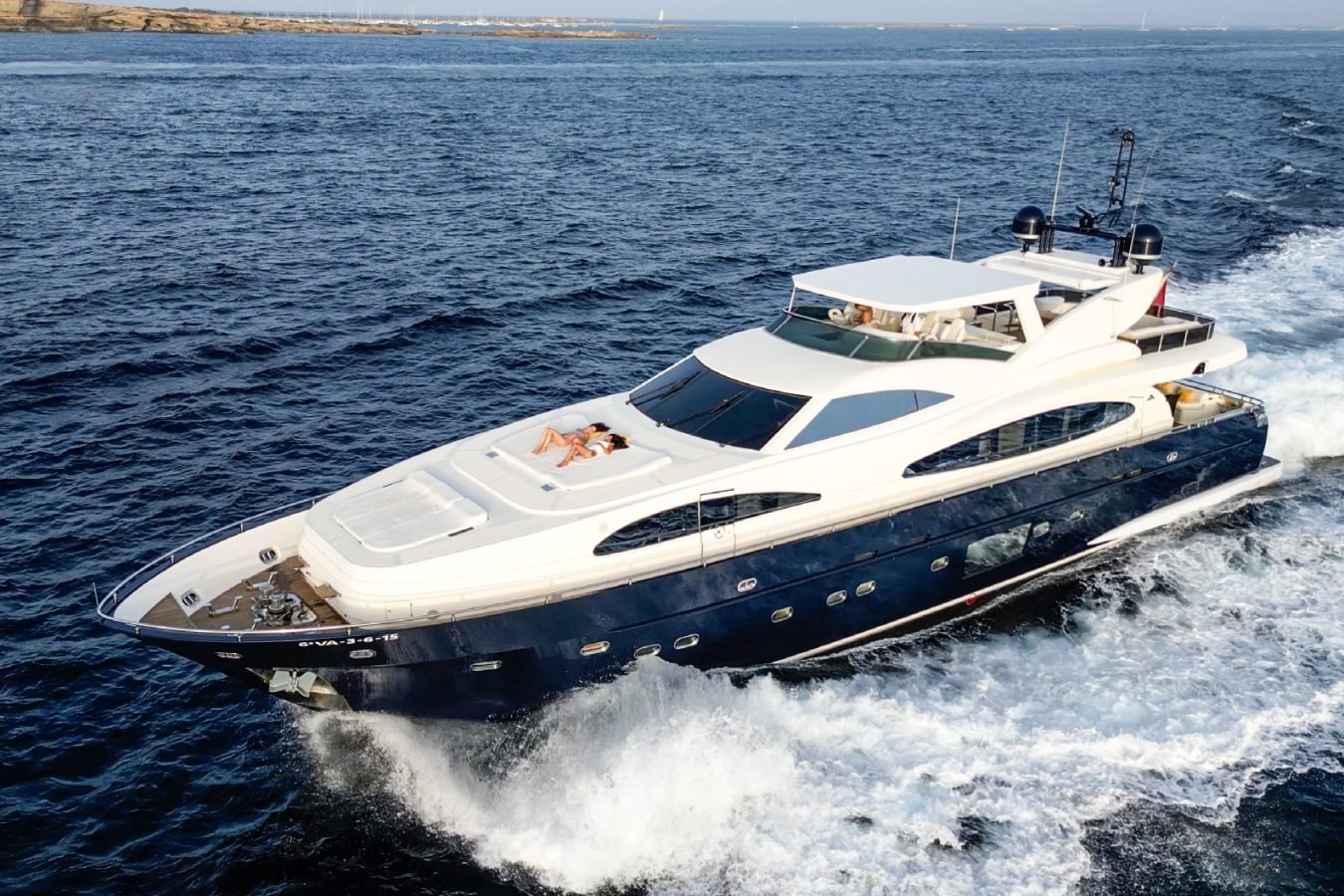 Astondoa 102 GLX My Kirios Yacht For Charter: Large white navy yacht speeds through blue ocean; two sunbathe on front deck.
