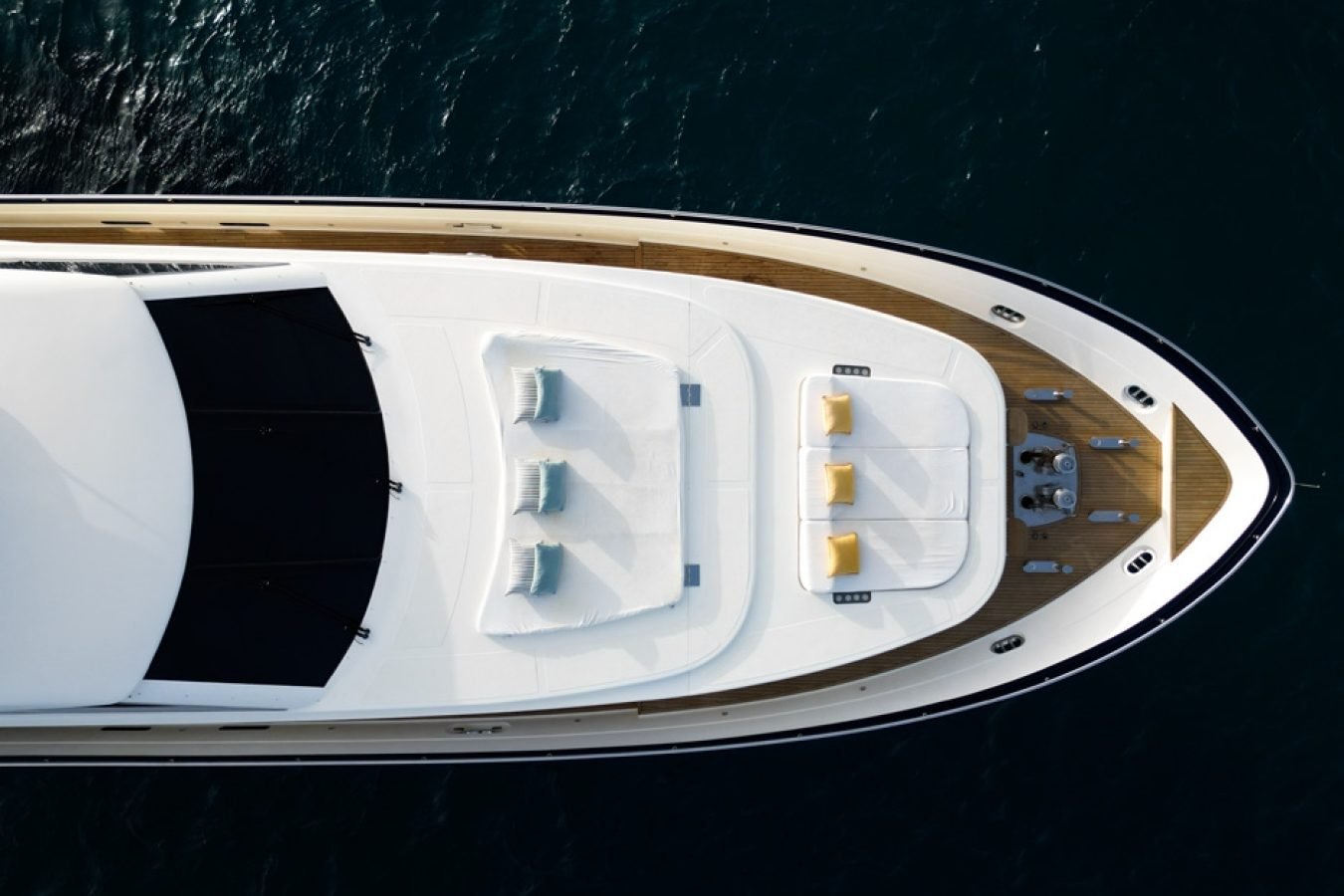Aerial view of Astondoa 102 GLX My Kirios Yacht For Charter with cushions, lounge chairs, and railing on calm blue sea.