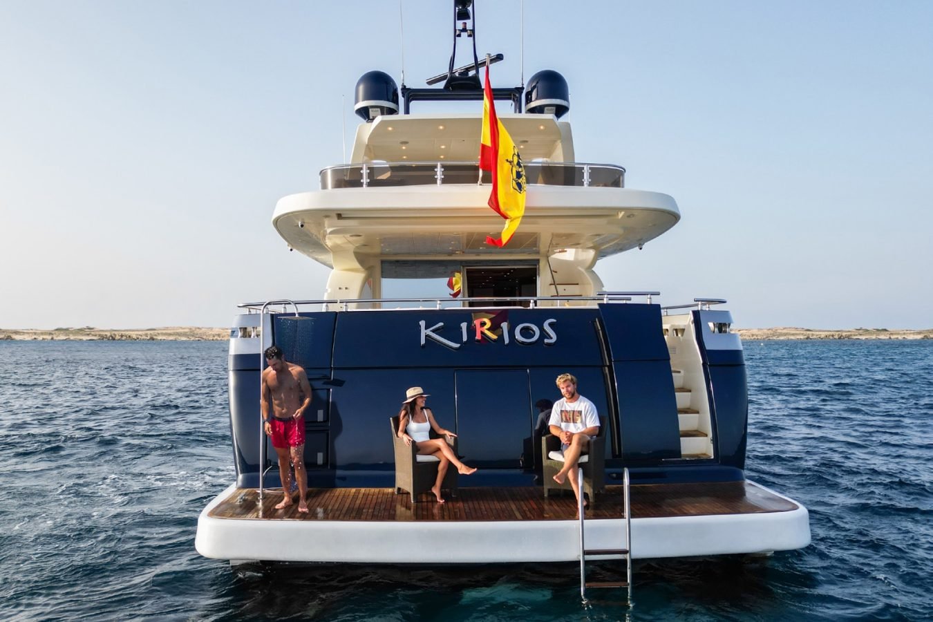 Three people relax on the Astondoa 102 GLX My Kirios Yacht For Charter, floating calmly, Spanish flag above.