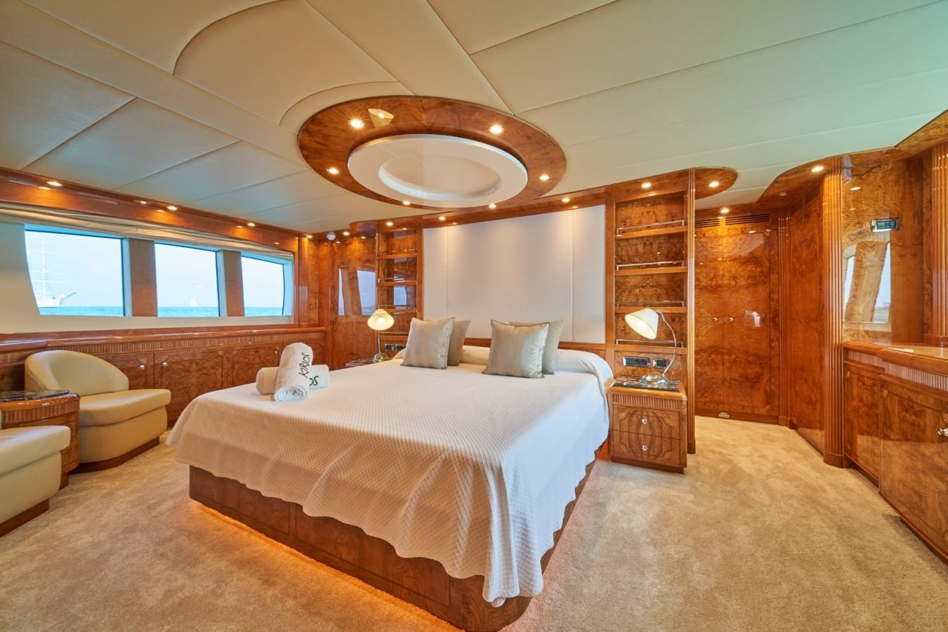Luxurious Astondoa 102 GLX My Kirios Yacht for Charter bedroom with wood paneling, large bed, and round ceiling lights.