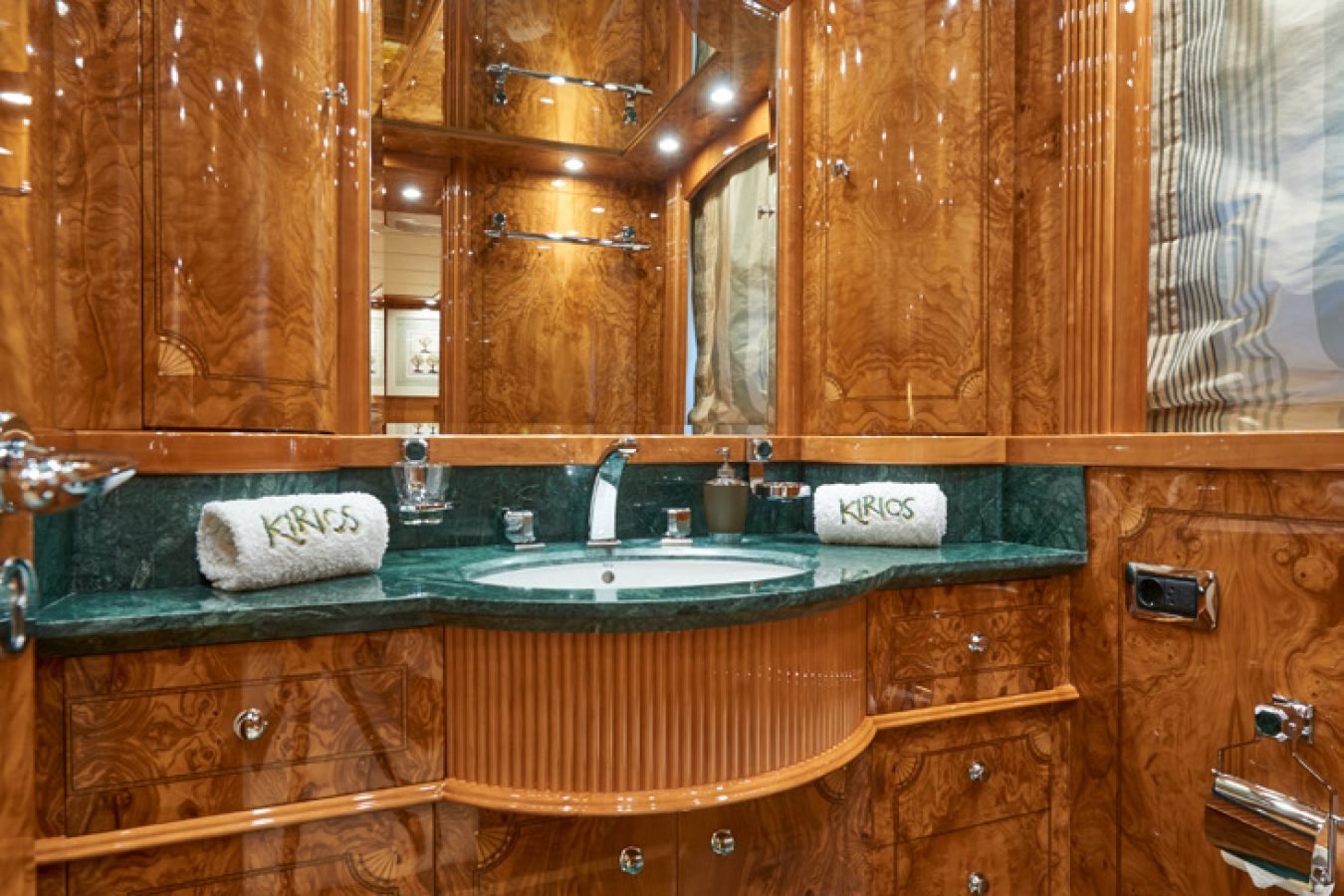 Luxurious bathroom aboard Astondoa 102 GLX My Kirios Yacht For Charter with wood cabinets, green marble, and chrome fixtures.