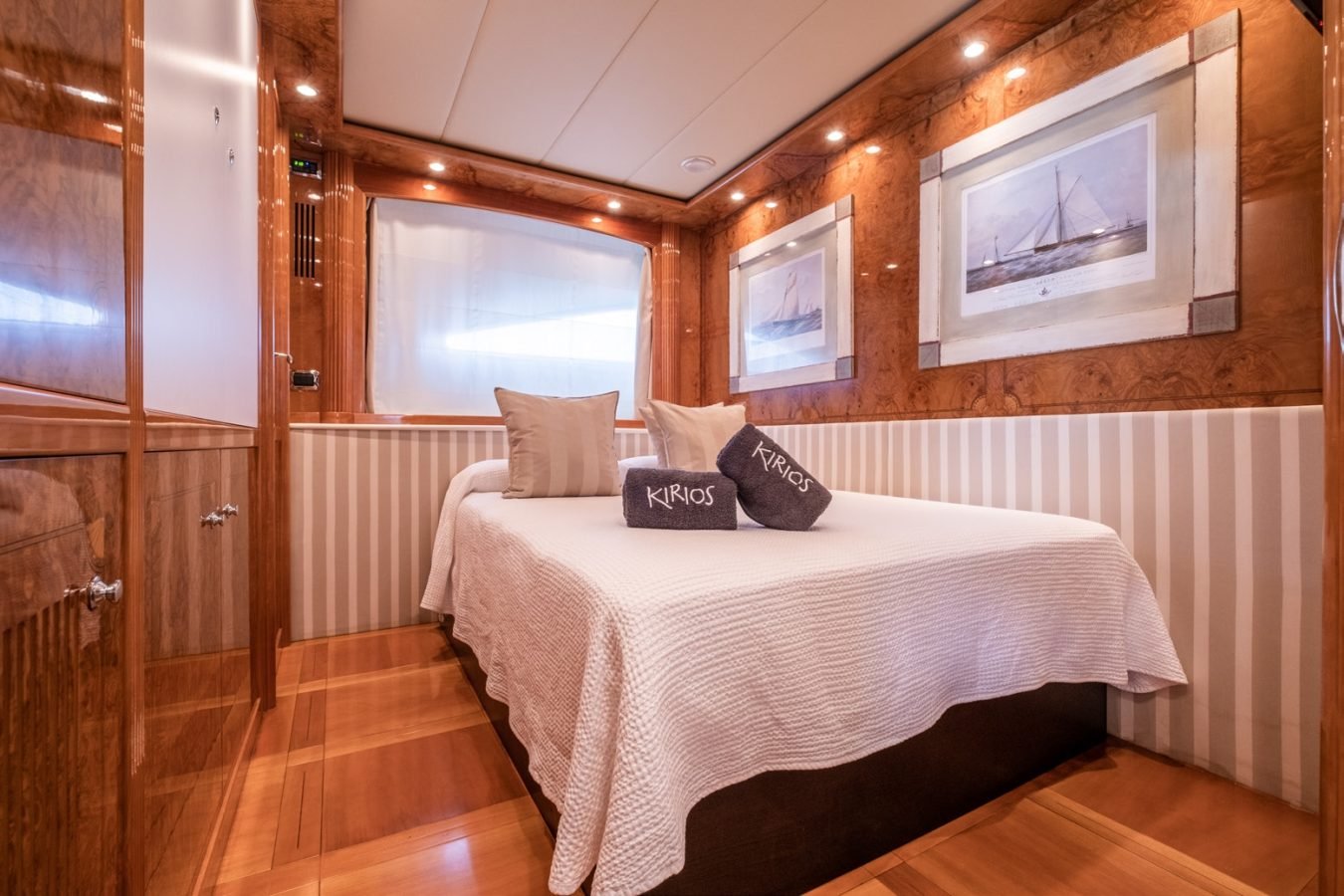 Cozy Astondoa 102 GLX My Kirios Yacht For Charter cabin with wood paneling, double bed, and framed sailboat art above.