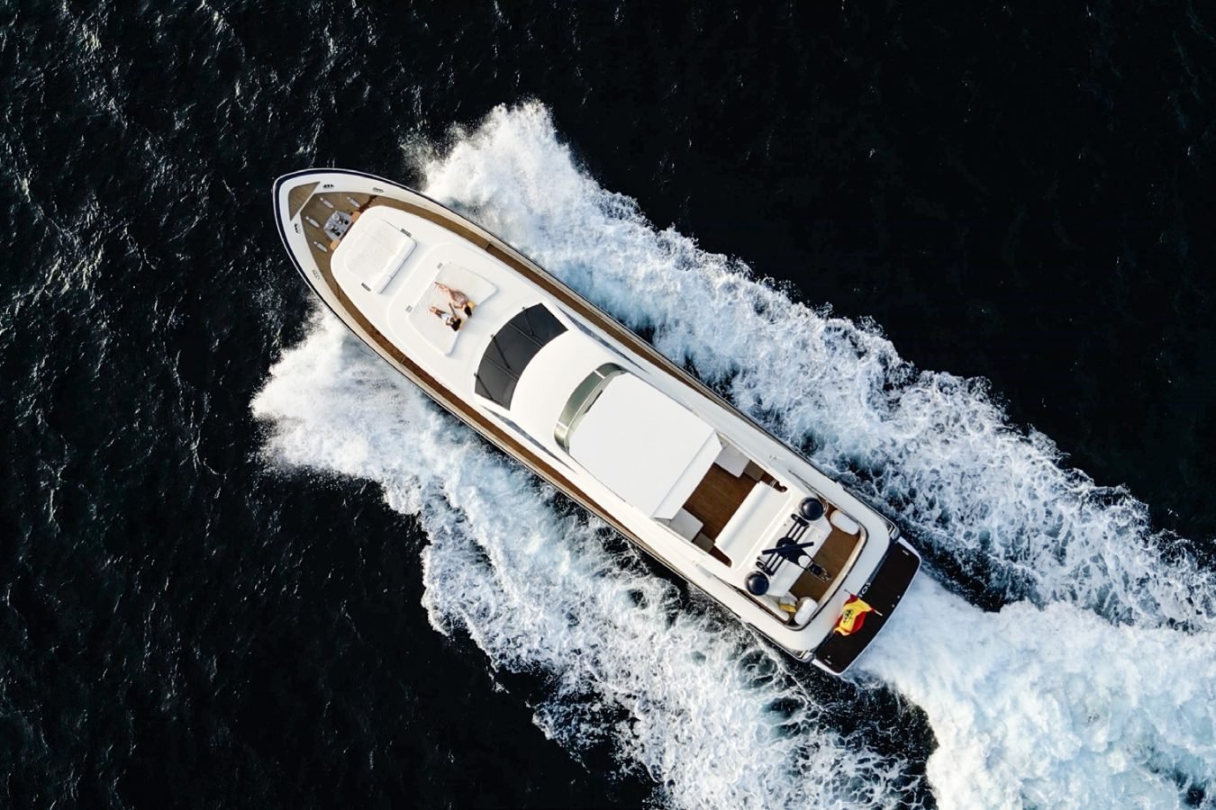 Aerial view of Astondoa 102 GLX My Kirios Yacht for charter, speeding through dark blue water with a foamy wake behind.