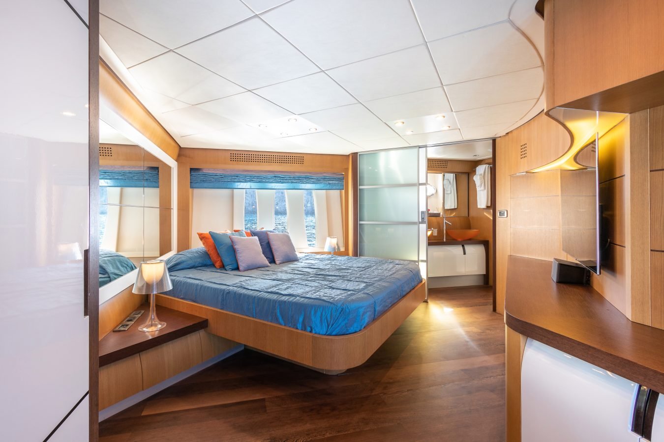 Modern Pershing 90 Inspiration Yacht For Charter with blue bedding, wood paneling, floating bed, mirrors, and orange sink.
