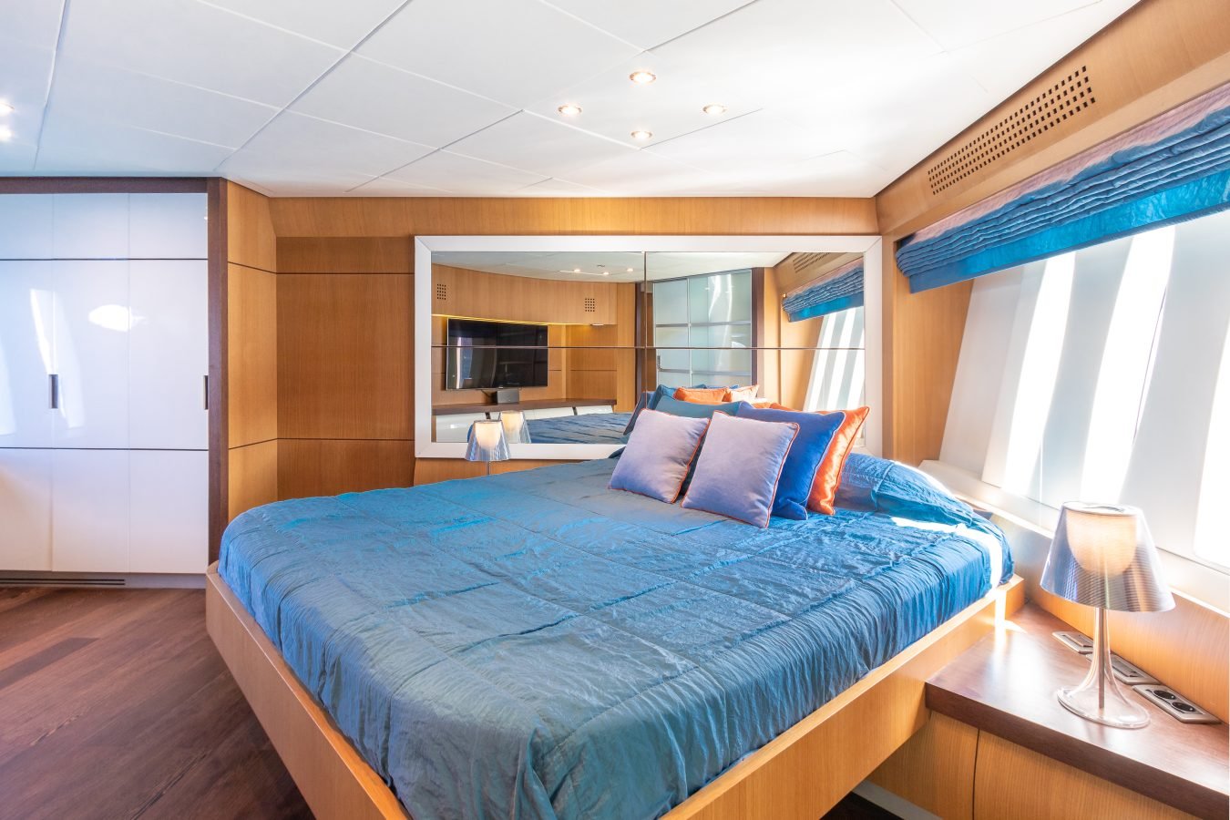 Modern bedroom with blue bedding, wood paneling, and a large mirror inspired by Pershing 90 Inspiration Yacht decor.