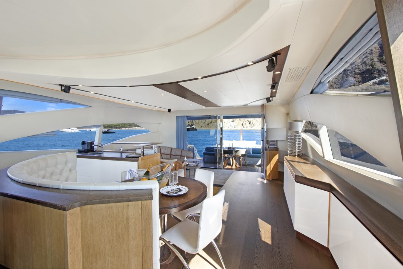 Modern Pershing 90 Inspiration Yacht for Charter with light wood, white furnishings, and sea views through open doors.