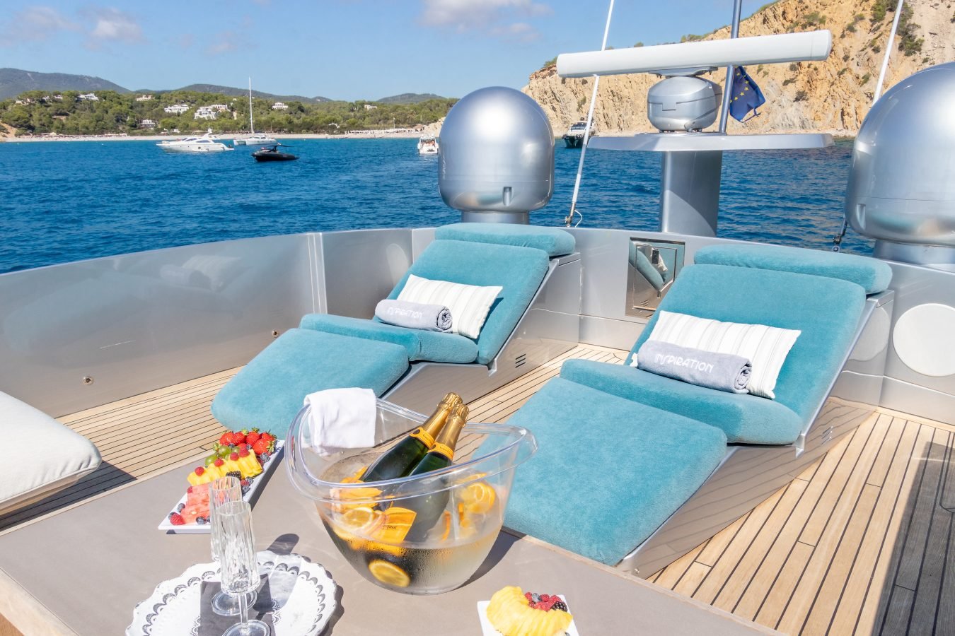 Two blue lounge chairs on the Pershing 90 Inspiration Yacht For Charter deck, with champagne and ocean views.