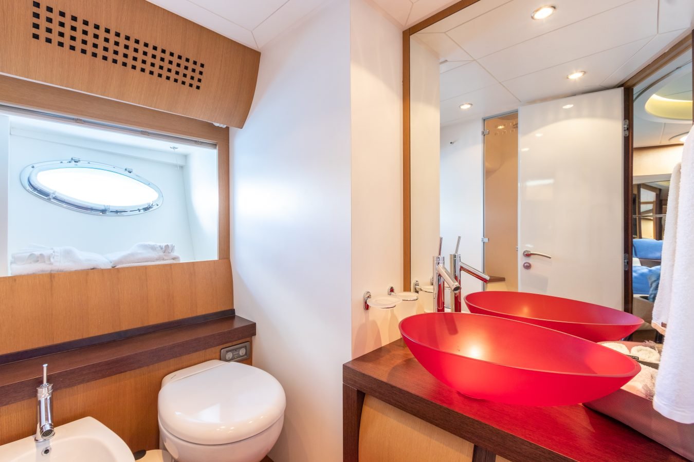 Modern yacht bathroom aboard Pershing 90 Inspiration Yacht For Charter, featuring red glass sinks and wood accents.