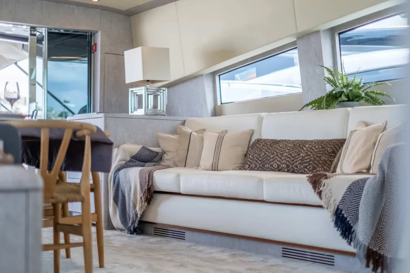 Relax in the LEOPARD 102 DARK KNIGHT Yacht lounge with a white sofa, chic decor, and panoramic windows.
