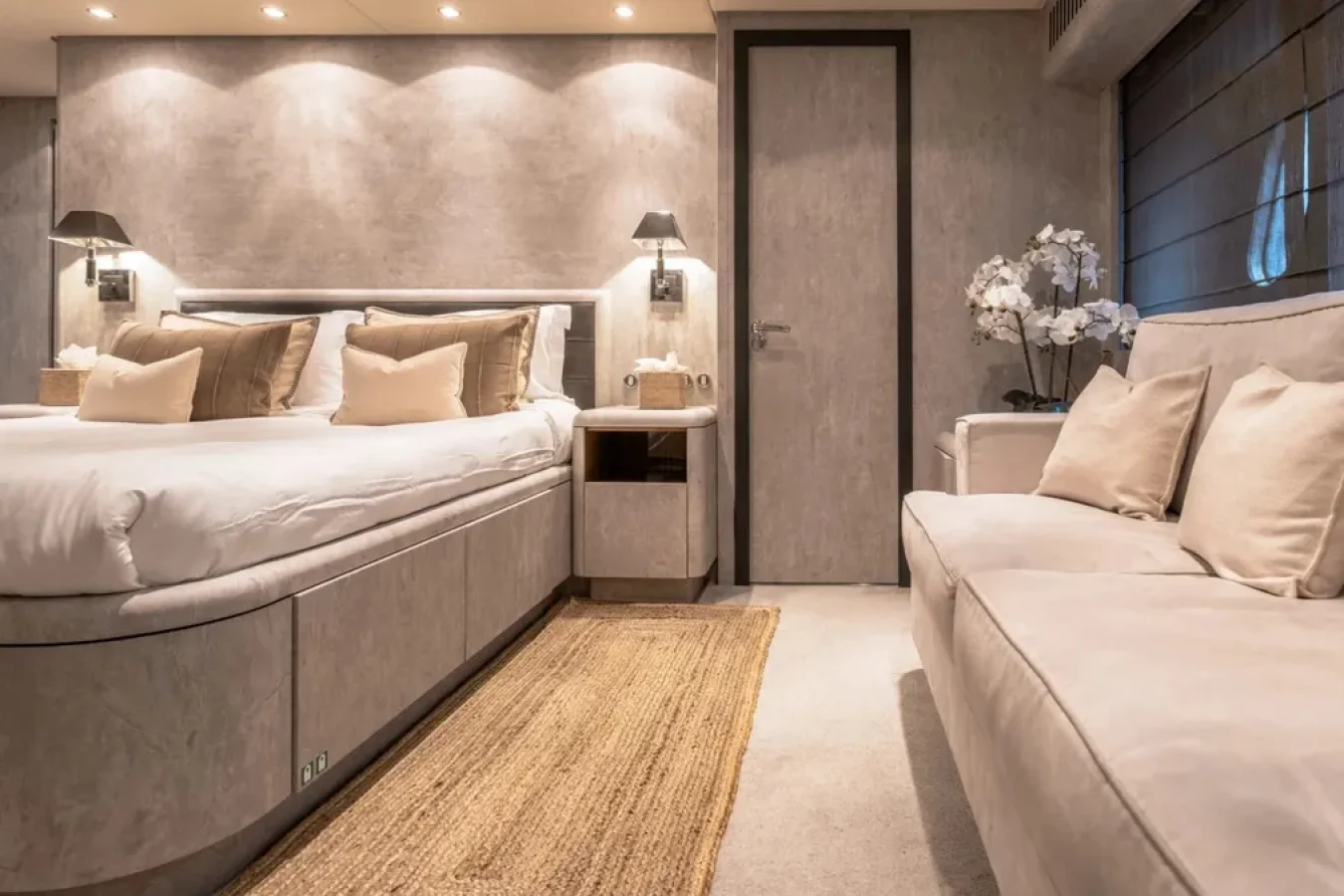 Modern bedroom with a cushioned bed, sofa, wall lamps, and décor inspired by the sleek style of LEOPARD 102 yachts.
