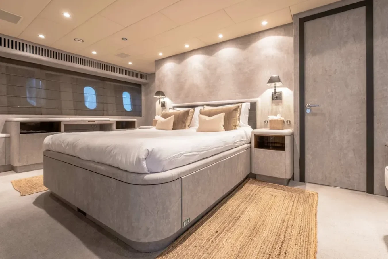 Modern yacht bedroom aboard LEOPARD 102 with large bed, wall sconces, wood accents, woven rugs—perfect yacht for charter.