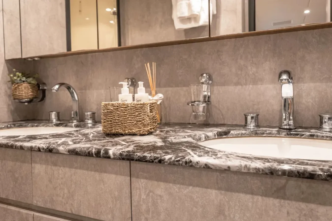 Double-sink bathroom with marble countertop on LEOPARD 102, plus wicker basket and wall mirror; perfect yacht for charter.