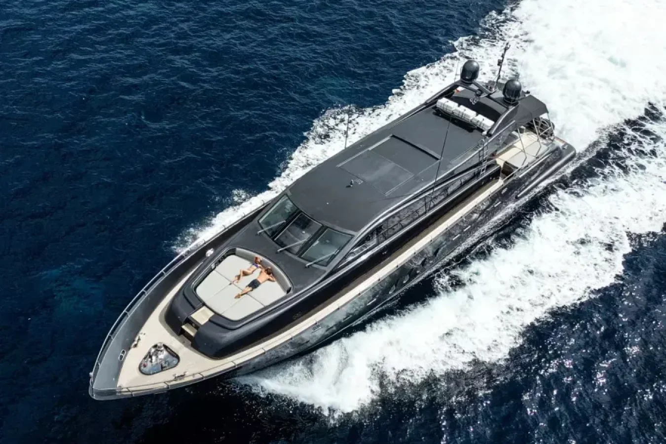 A sleek LEOPARD 102 speeds across blue water; a person lounges on the bow, sunbathing under a clear sky.