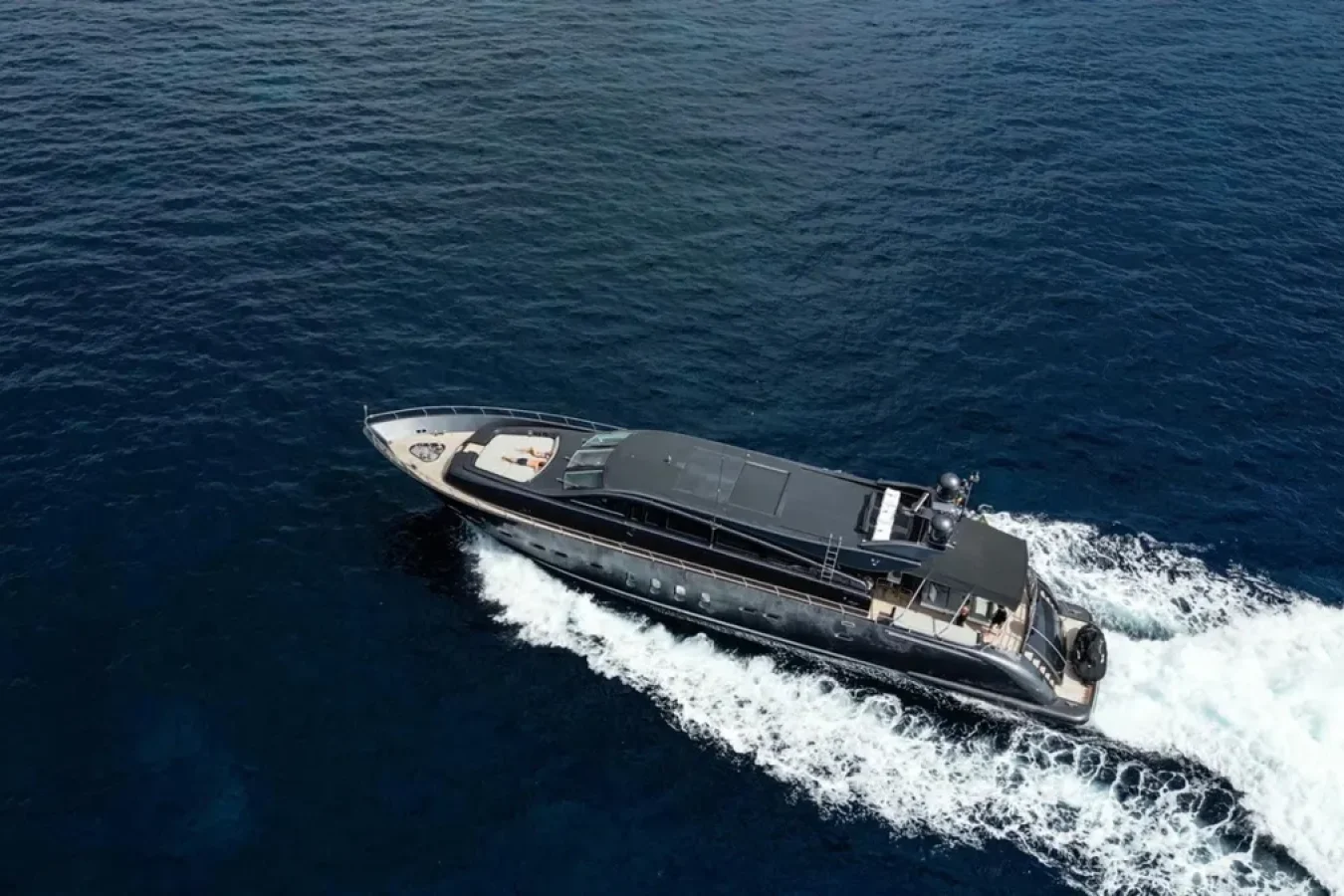 The DARK KNIGHT Yacht, a sleek LEOPARD 102, moves swiftly through deep blue water, leaving a white foamy wake.