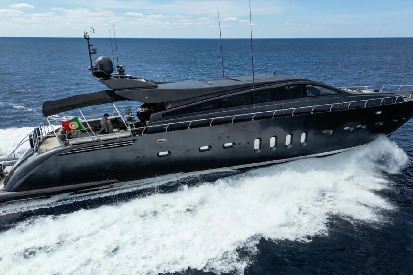 DARK KNIGHT Yacht, a LEOPARD 102, cruises at speed on open blue sea, leaving frothy waves in its wake under clear sky.