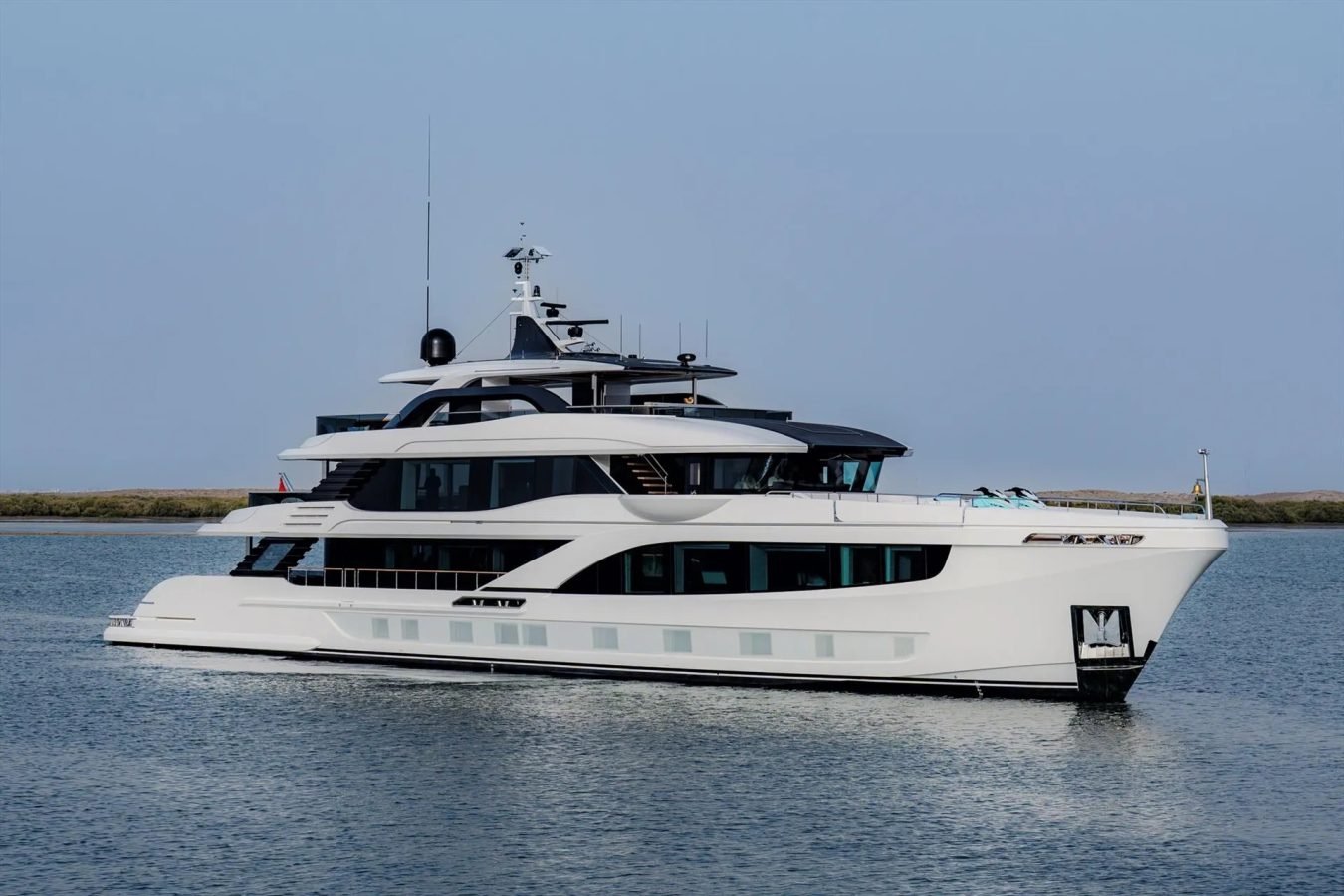 A Majesty 145 superyacht cruises on calm water, featuring a modern white multi-deck design with tinted windows.