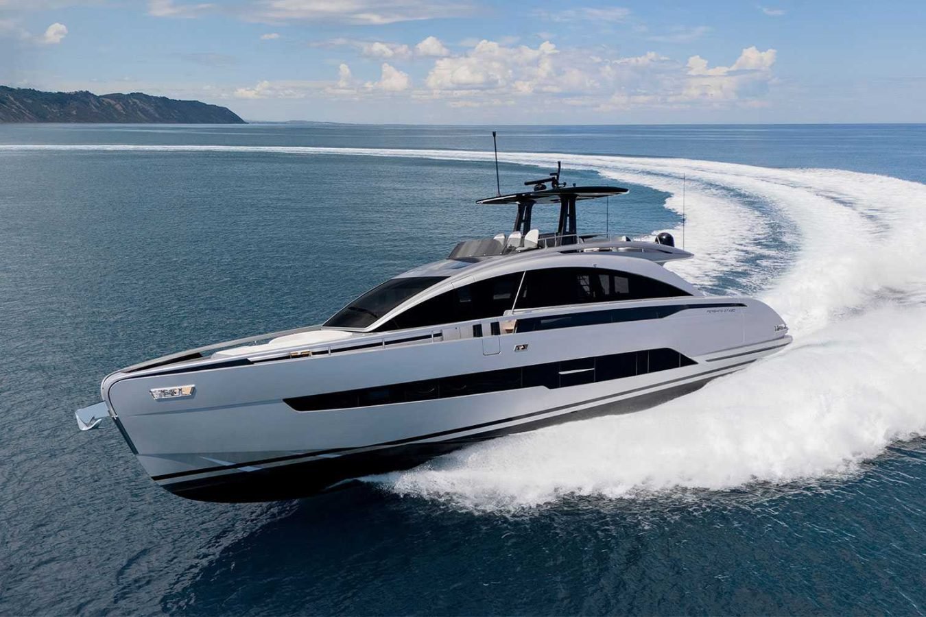 A sleek Pershing Gtx80 yacht for charter speeds across calm blue water, leaving a striking curved white wake behind.