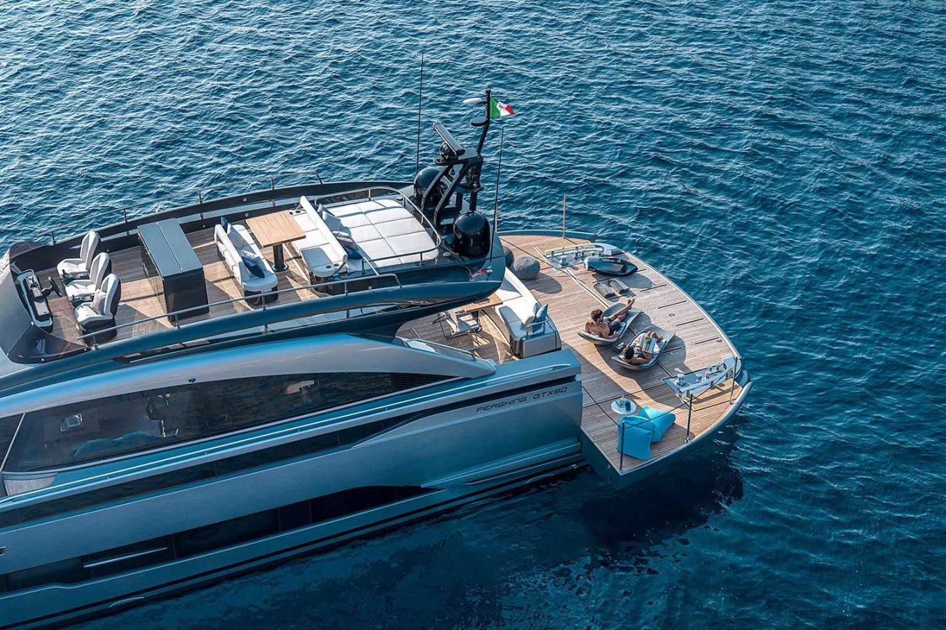 Luxury Pershing Gtx80 yacht for charter with sun loungers and guests relaxing, floating on calm, deep blue water.