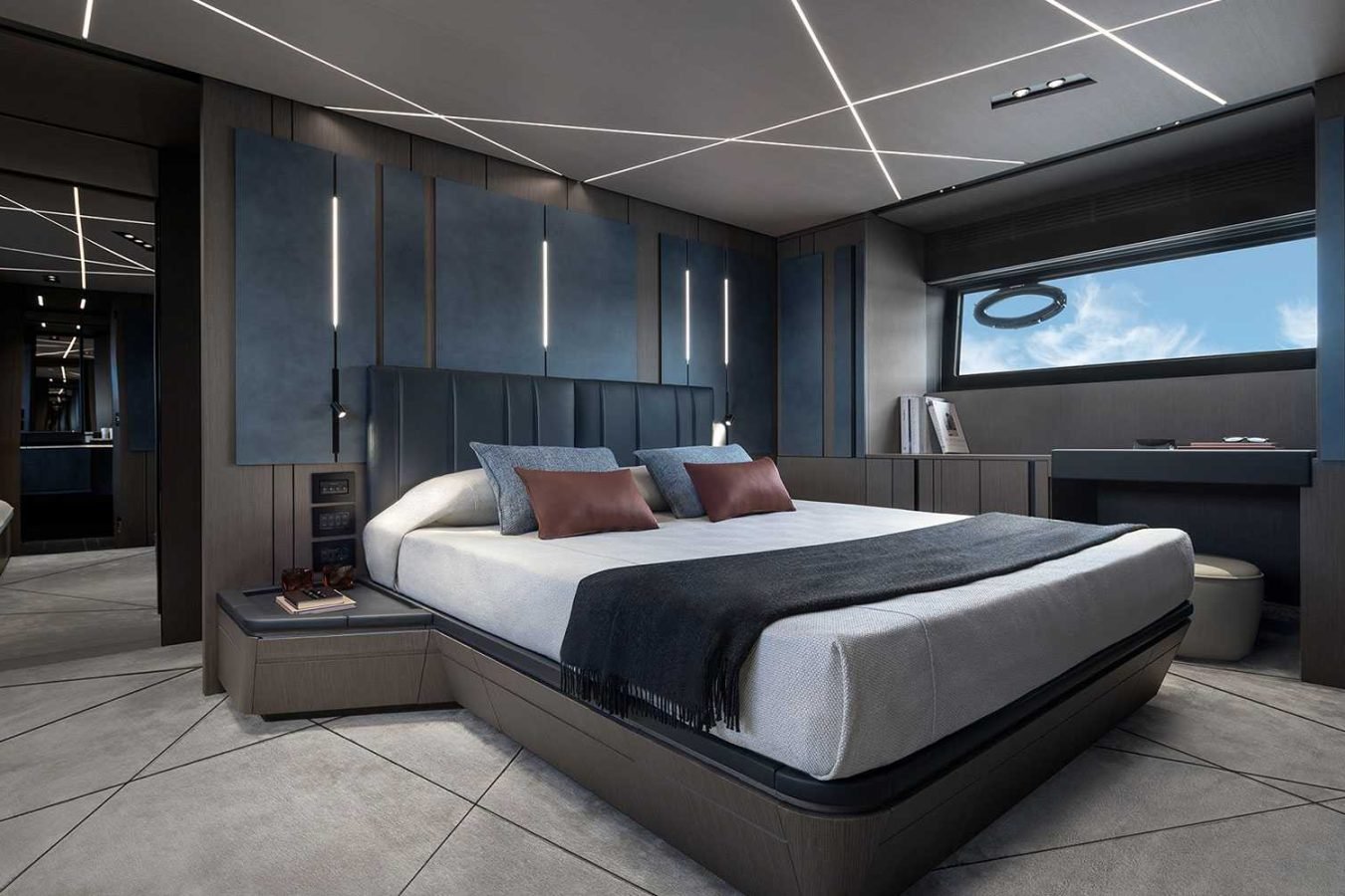 Modern bedroom with geometric lighting, blue accents, large bed—yacht for charter vibes and window showing blue sky.