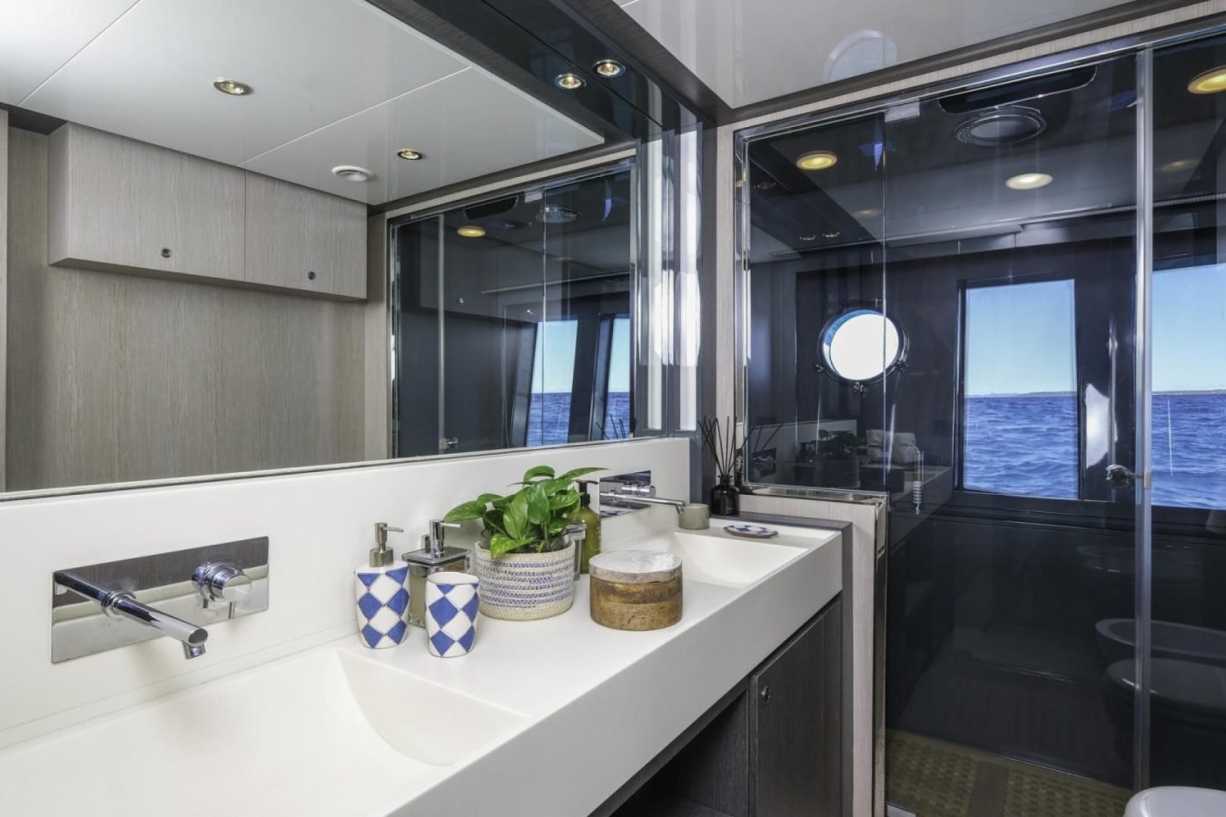 Modern Riva 86 Tanit yacht bathroom with double sink, sea views, plants, and sleek mirrors—perfect for your yacht charter.
