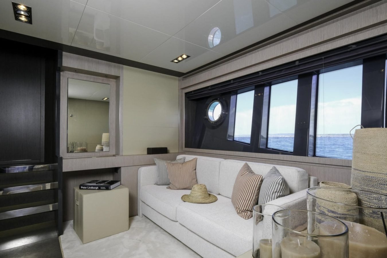 Modern yacht lounge on Riva 86 with white sofa, candles, sea views, and mirror—perfect for a Tanit yacht for charter.