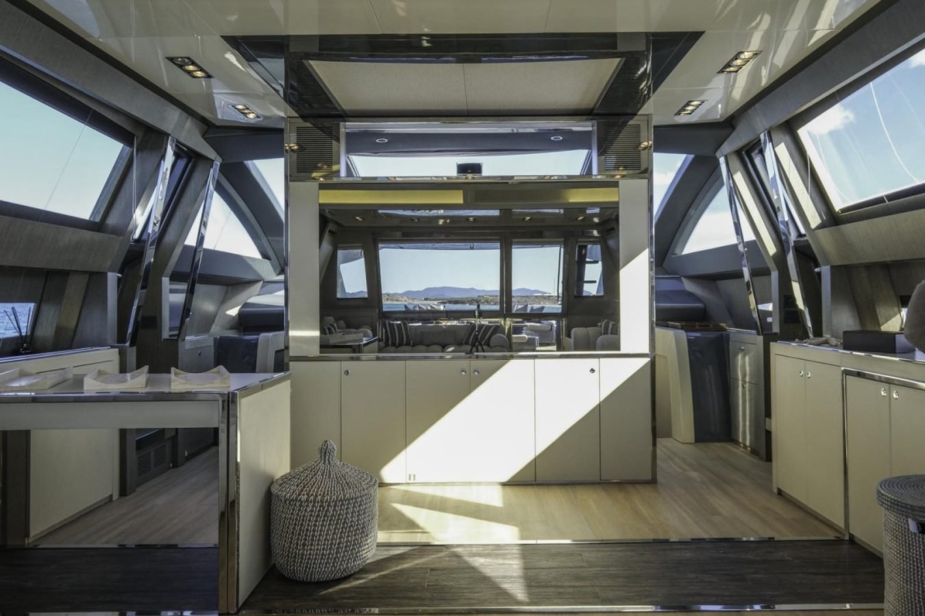 Modern yacht interior with wood floors, sunlight, and ocean view—perfect for a Riva 86 Tanit yacht charter experience.