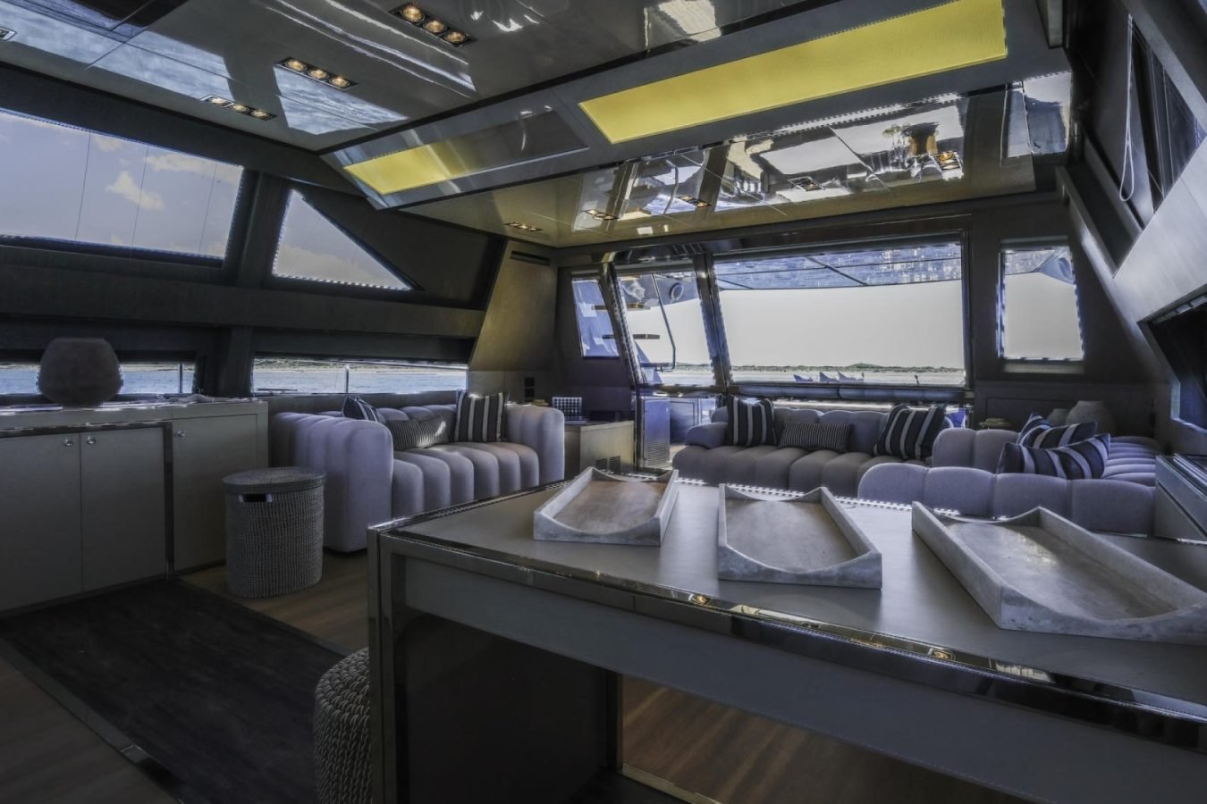 Modern Riva 86 Tanit yacht for charter with striped sofas, water views, and a reflective ceiling.