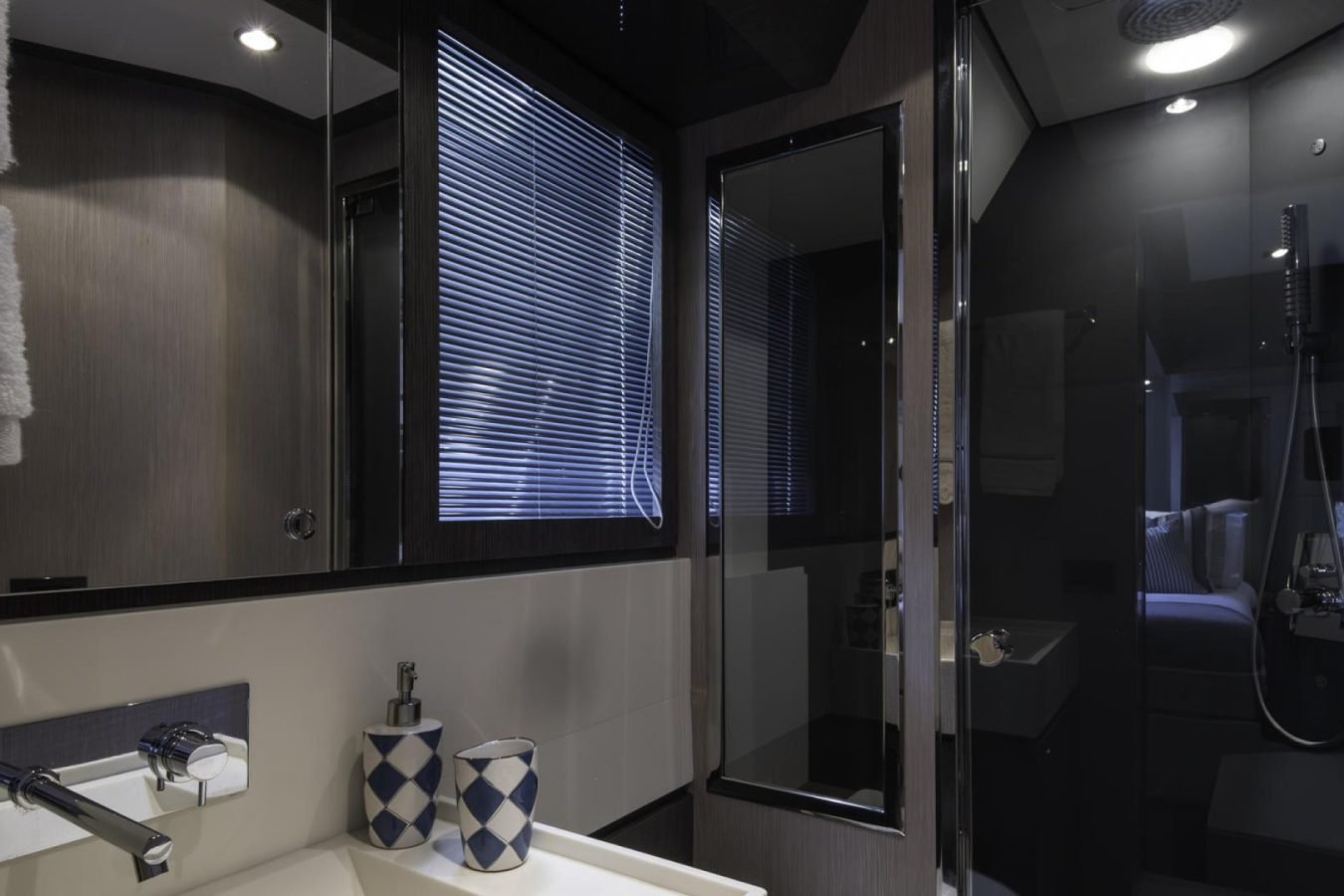 Modern bathroom with white sink, geometric cups, and glass shower—luxury like a Riva 86 Tanit yacht for charter.