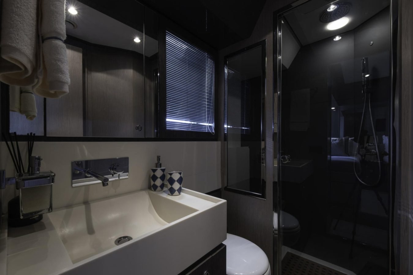 Modern bathroom on Riva 86 Tanit yacht for charter, featuring a rain showerhead and geometric soap dispenser.
