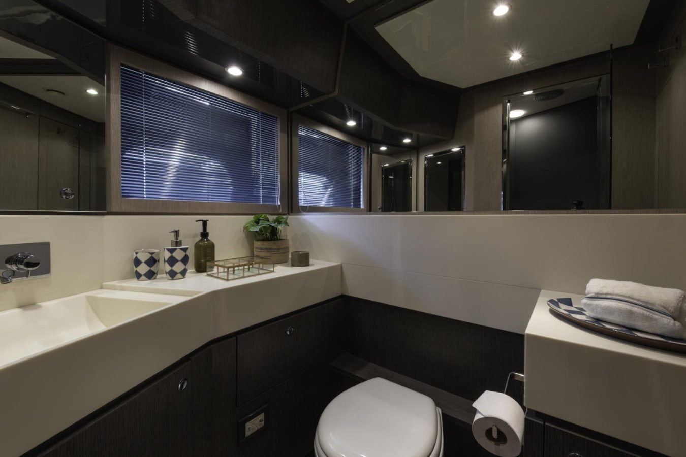 Modern bathroom with a square sink, towels, and window blinds—perfect for a Riva 86 Tanit yacht for charter.
