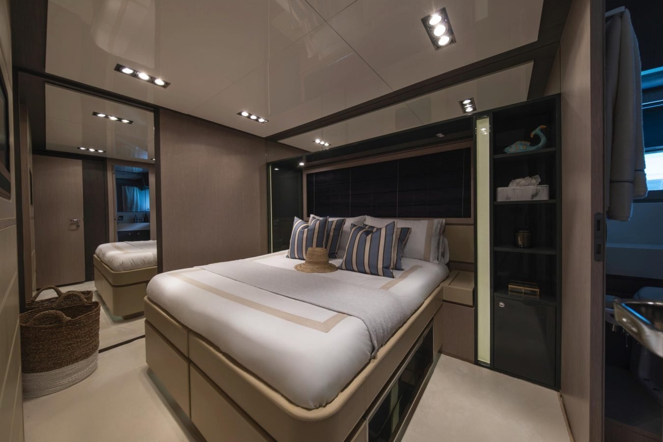 Modern yacht bedroom on Riva 86 Tanit with a large bed, striped pillows, mirrored wall, and ambient lighting.