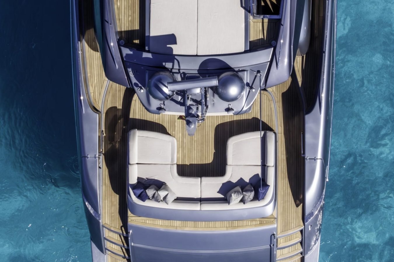 Aerial view of Riva 86 Tanit’s cushioned deck, wood flooring, and blue ocean—perfect for a luxury yacht charter.