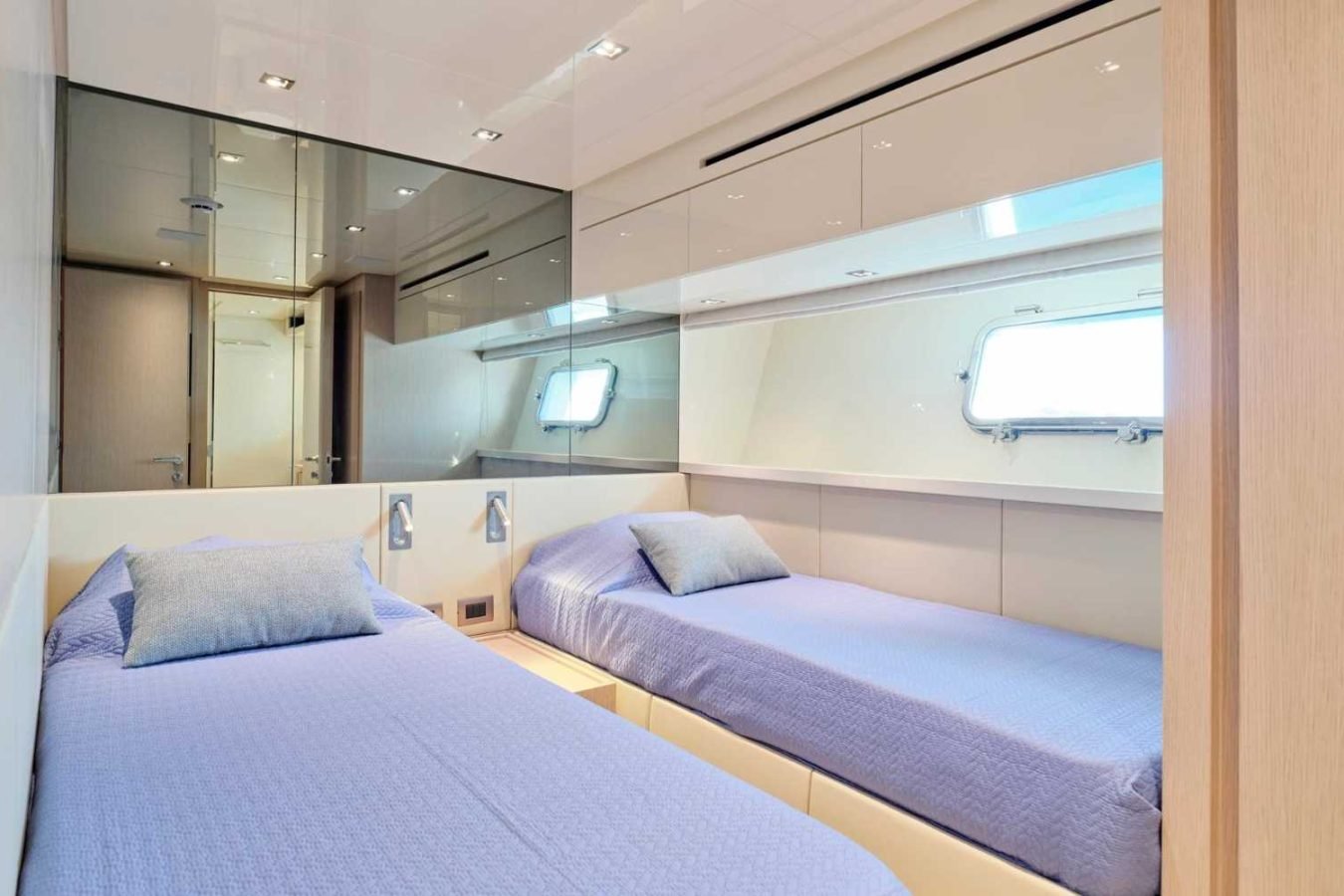 Modern Sanlorenzo SX76 Fuquet Duet yacht cabin with two single beds, blue bedding, wood paneling, and bright natural light.