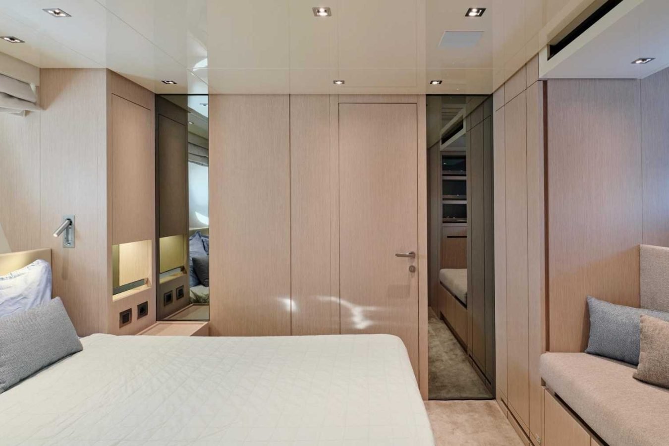 This modern bedroom on the Sanlorenzo SX76 Fuquet Duet features light wood walls, sleek closets, and a cozy small sofa.
