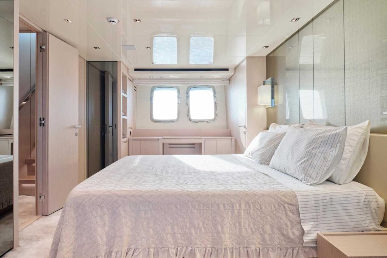 Bright Sanlorenzo SX76 Fuquet Duet yacht bedroom with large bed, mirrored panels, and modern, minimal decor.