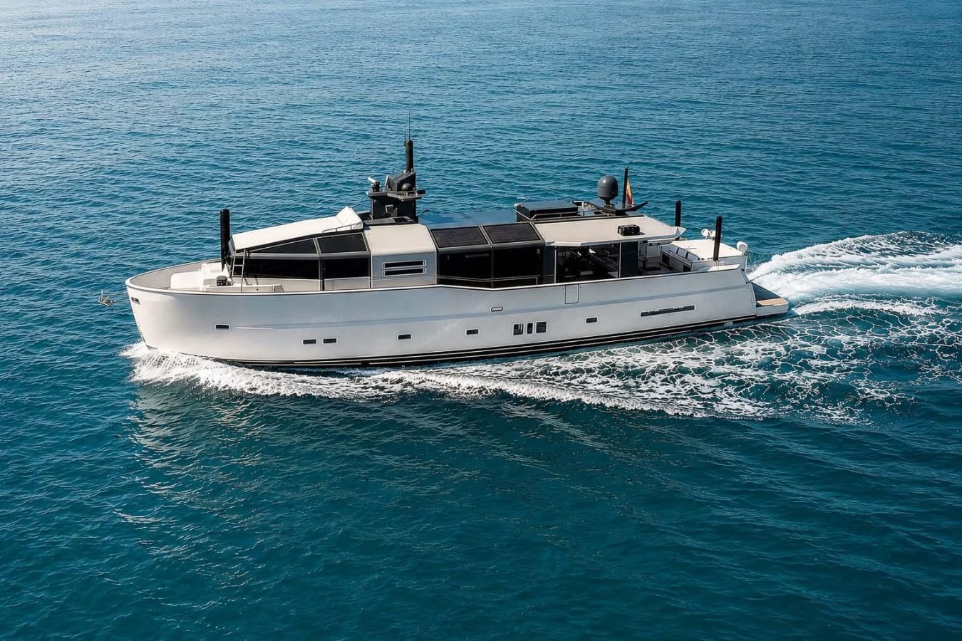 The Arcadia 85 Dhamma II yacht for charter glides swiftly, leaving a foamy wake across the calm, blue ocean.