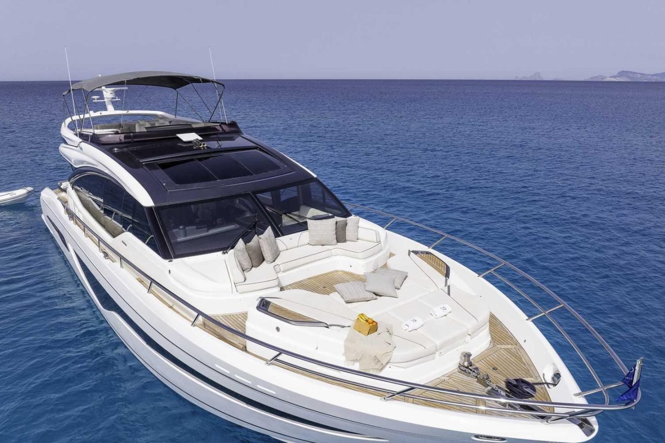 White Princess S78 luxury yacht, Why Knot, with sunbathing area and lifebuoy, floats calmly on blue ocean under clear skies.