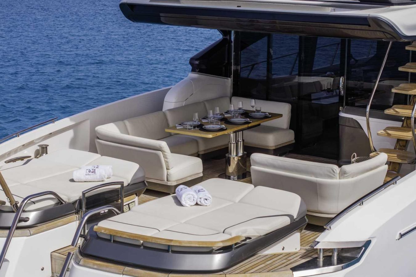 Luxurious Princess S78 yacht for charter with cushioned seating, dining table, loungers, and calm blue water views.
